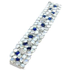 An absolutely stunning bracelet by Sophia D.! There are a total of 77 cabochon cut Moonstones prong set throughout the bracelet and 12 cabochon cut Sapphires, with emerald cut and round brilliant Diamonds. The Moonstones display beautiful adularescence in every stone. The cabochon Sapphires are a rich royal blue color and have a total weight of 20.60 carats, and are off set with handcrafted round brilliant pave Diamond leaves and emerald cut Diamonds. The Diamonds have a total weight of 3.50 car Luxury Silver Bracelets With Cabochon, Elegant White Cabochon Gemstones, Cabochon Bracelet, 18k Gold Bracelet, Royal Blue Color, Emerald Cut Diamonds, Sapphire Diamond, Moon Stone, Emerald Cut