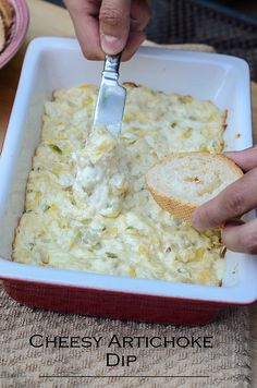 someone spreading cheese on top of bread in a red dish