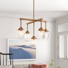 a living room with a couch, table and chandelier hanging from the ceiling