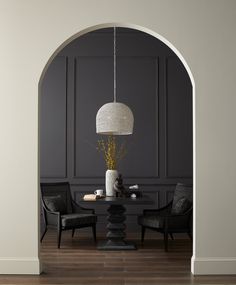 a dining room table with two chairs and a vase on the table next to it