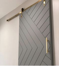 the door is painted gray and has gold hardware on it's sides, along with a white wall