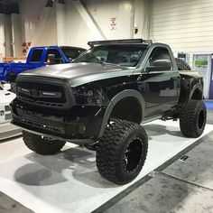 a black truck is on display in a showroom with other trucks and equipment behind it