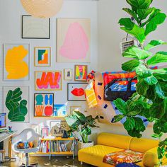 a living room filled with lots of plants and pictures on the wall above it's couches