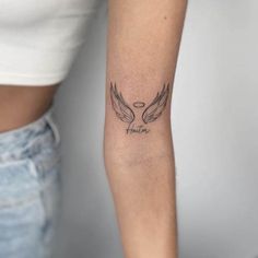 a woman's arm with an angel wing tattoo on the left side of her arm