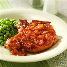 a white plate topped with meat covered in sauce next to green beans and broccoli