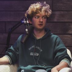 a young man sitting in front of a microphone