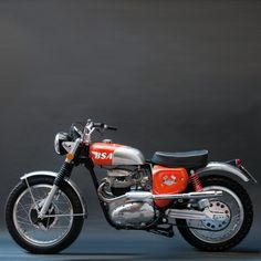 an orange and silver motorcycle parked in front of a gray background