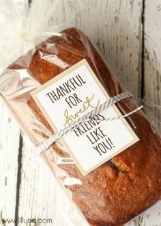 a loaf of bread wrapped in plastic on top of a wooden table with a thank you sign