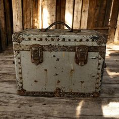 an old suitcase sitting on top of a wooden floor next to a wall and fence