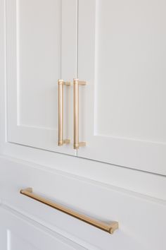 a white cabinet with brass handles and pulls