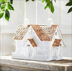 a white house with brown shingles on the roof is sitting on a piece of wood