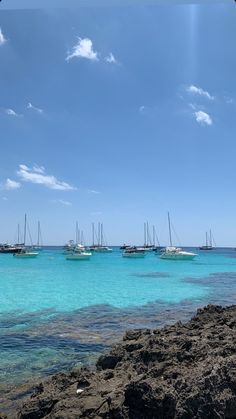 several boats floating in the ocean on a sunny day