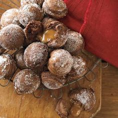 a bunch of doughnuts sitting on top of a wooden table next to a red cloth