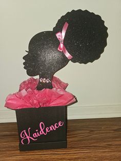 a black box with a pink ribbon and a silhouette of a woman's head