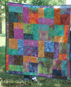 a woman standing next to a colorful quilt