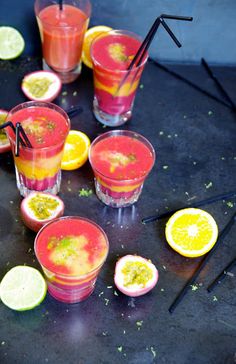 several glasses filled with different colored drinks and garnished with lemons, limes, and strawberries