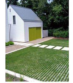 an image of a small white house with green doors and grass on the lawn in front of it