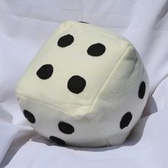 a white and black dice laying on top of a white cloth covered sheet with black dots