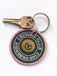 a keychain with the words leisure club written on it and a lion emblem