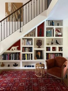 a living room filled with lots of furniture and bookshelves next to a stair case