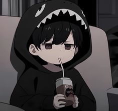 a person sitting on a chair with a drink in their hand and wearing a shark hoodie