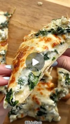 someone is holding a slice of pizza with spinach and cheese