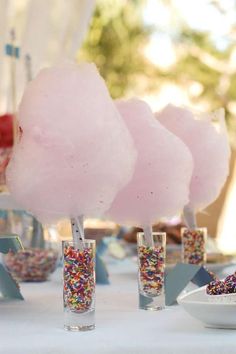 pink cotton candy lollipops on sticks with sprinkles in them