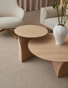 a white vase sitting on top of a wooden table next to a couch and chair