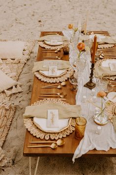 a table set up on the beach with place settings