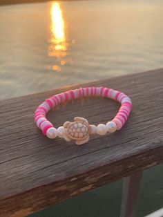 Enjoy this beautiful pink and white hand-crafted bracelet with clay beads and a beige Turtle central charm.. Bracelet is elastic banded and stretches to fit an average size female wrist. Celebrate summer with this fun jewelry. Clay Bead Bracelet Ideas Turtle, Turtle Charm Bracelet, Cute Braclets To Make Yourself, Pink Hand-strung Stretch Bracelet For Beach, Cute Summer Bracelet Ideas, Preppy Bracelet Ideas Summer, Clay Beads Ideas Summer, Turtle Clay Bead Bracelet, Beach Clay Bead Bracelet Idea