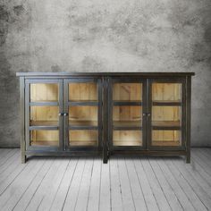 a wooden cabinet with glass doors in an empty room