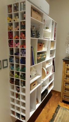 a white book shelf filled with lots of crafting supplies on top of a hard wood floor