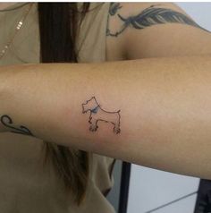 a woman's arm with a small dog tattoo on the left side of her arm