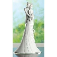 a bride and groom figurine sitting on top of a table next to a window