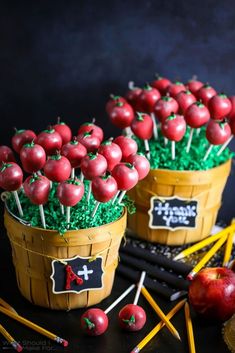 two wooden baskets filled with cherries on top of a table next to pencils