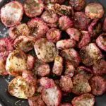 cooked red potatoes with herbs in a black bowl