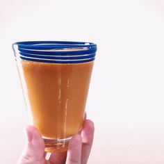 a person holding up a glass with some liquid in it's bottom and two hands on the side