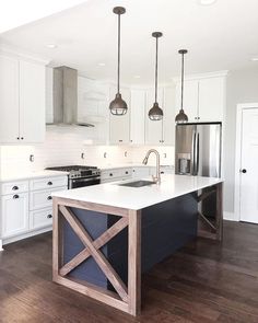 a large kitchen with an island in the middle and two pendant lights hanging from the ceiling