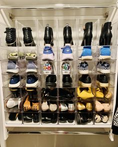 several clear bins filled with various pairs of shoes on display in front of a white wall