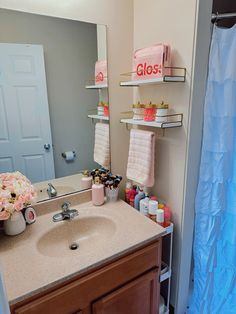 a bathroom sink with pink towels hanging on the rack above it and a blue shower curtain