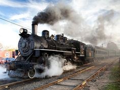 an old fashioned steam train is traveling down the tracks