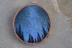 a painted wooden bowl with trees and stars in the night sky on it's surface