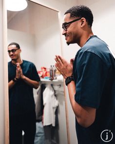 two men are standing in front of a mirror and clapping their hands to each other