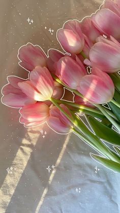 a bouquet of pink tulips sitting on top of a white cloth covered table