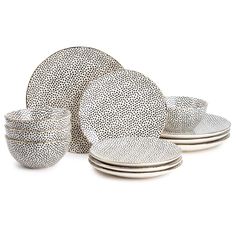 a set of four white and black dinnerware with dots on the rims,