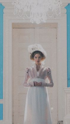 a woman standing in front of a door wearing a white dress and holding her hands on her hips