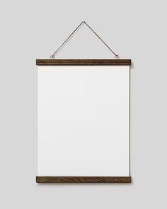 a white board hanging on a wall with a wooden frame and string attached to it