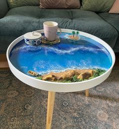 a coffee table with an ocean scene painted on the top and two mugs sitting on it