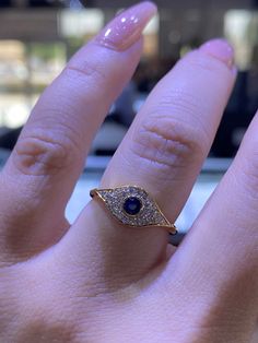 a woman's hand with a ring on it that has a blue stone in the middle