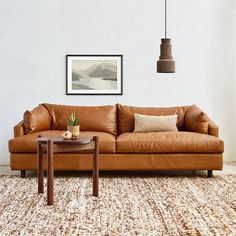 a living room with a brown leather couch and coffee table in front of a white wall